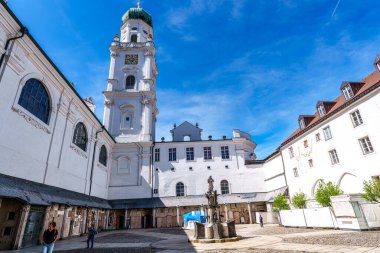 Passau, Almanya - 16 Nisan 2025: Passau, Almanya 'daki St. Stephans Katedrali kulelerin tepesinde yeşil metal kubbeler bulunan eski bir beyaz kilisedir. Kilisenin önünde Maximillian Joseph 'in heykeli var.