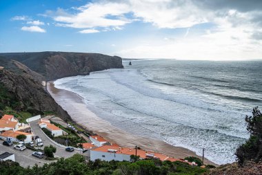 Portekiz 'in vahşi batı kıyısındaki yüksek uçurumlar tarafından çerçevelenmiş Praia da Arrifana sahilinin muhteşem manzarası. Sörfçülerin çok sevdiği bir plaj.