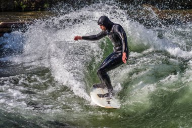 Münih, Almanya - 13 Aralık 2024: Münih şehir nehrinde kış sörfçüsü, Almanya 'nın Münih kentsel çevrede Eisbach adı verilen sörfçüsüyle meşhurdur.