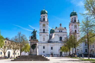 Passau, Almanya - 16 Nisan 2025: Passau, Almanya 'daki St. Stephans Katedrali kulelerin tepesinde yeşil metal kubbeler bulunan eski bir beyaz kilisedir. Kilisenin önünde Maximillian Joseph 'in heykeli var.