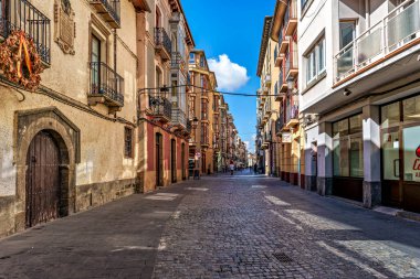Jaca, İspanya - 16 Ekim 2025: Jaka, Huesca, Aragon, İspanya 'da pencereli düşük pastel renkli evler ve oyulmuş metal balkonlar. Sokak çizgileri Jaca 'nın eski kasabasına ve Havari Aziz Peter Katedrali' ne çıkıyor..