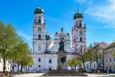 Passau, Almanya - 16 Nisan 2025: Passau, Almanya 'daki St. Stephans Katedrali kulelerin tepesinde yeşil metal kubbeler bulunan eski bir beyaz kilisedir. Kilisenin önünde Maximillian Joseph 'in heykeli var.