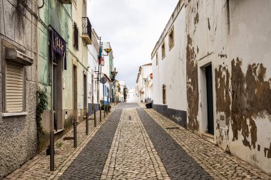 Lagos, Portekiz - 22 Şubat 2026: Portekiz 'deki Lagos' un tarihi bölümü. Calcada Portuguesa adı verilen geometrik desenlerle döşenmiş sokak boyunca geleneksel renkli evler