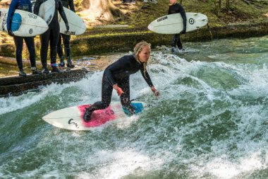 Münih, Almanya - Haziran 04, 2024: Münih şehir nehri sörfçüsü, Münih 'teki İngiliz Bahçesi' nde Eisbach adı verilen kentsel çevrede sörf yapan insanlarla ünlüdür.
