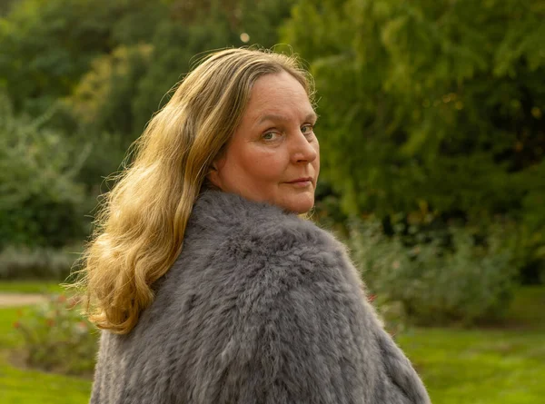在城市公园拍照时穿着兔毛夹克的女人 — 图库照片
