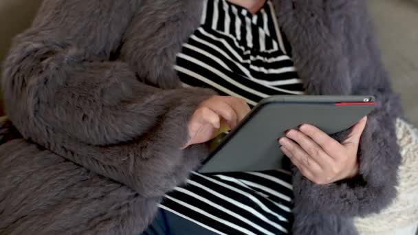 穿着兔毛夹克的女人在家里的办公室里和平板电脑一起工作 — 图库视频影像