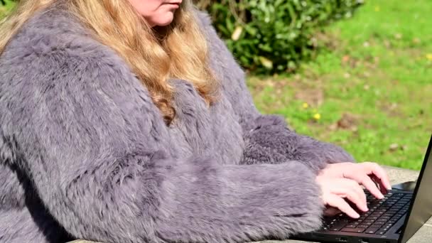 ウサギの毛皮のジャケットの女性は 自宅のオフィスでノートと庭で動作します — ストック動画