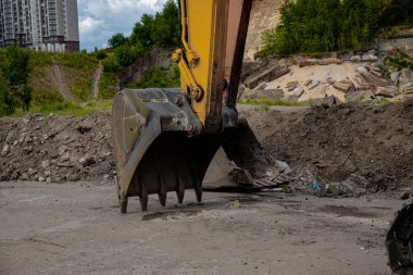 Şehrin ortasındaki bir taş ocağının kazısında duran sarı bir kazıcı. Eski, kirli bir kazıcı. özel ekipman