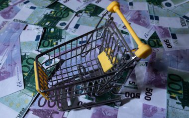 İlaçlar ve haplar küçük bir alışveriş arabasında, paranın arka planında yatıyor. 100 avro 500 dolar. Para için arabadan haplar dökülüyor. İlaçların maliyeti çok yüksek.