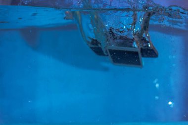 Siyah beyaz telefon suya düştü. Suda telefon. Su kabarcıklarında telefon. Telefon suya batıyor.