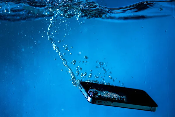 Siyah beyaz telefon suya düştü. Suda telefon. Su kabarcıklarında telefon. Telefon suya batıyor.