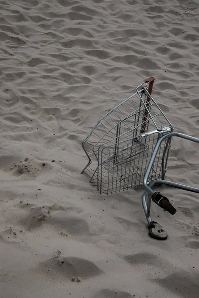 超市商店的购物车躺在沙漠的白沙中间 文明对自然的污染 破坏自然 人类在乱扔垃圾人类在污染 — 图库照片
