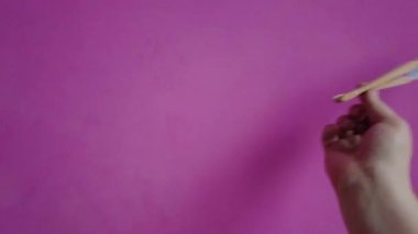 Bir el pembe arka planda bir yelpaze açar.