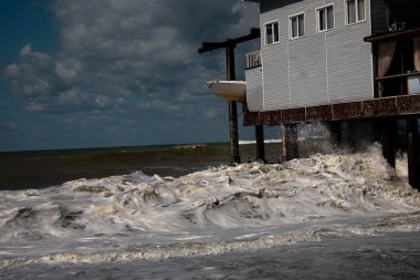 Deniz dalgaları fırtınada evi dövüyor. Siyah deniz mavi gökyüzü dalgalı deniz fırtınası