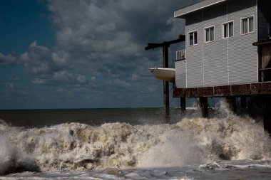 Deniz dalgaları fırtınada evi dövüyor. Siyah deniz mavi gökyüzü dalgalı deniz fırtınası