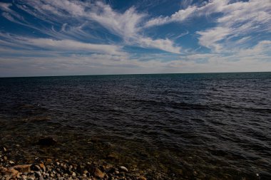 Mavi gökyüzü ve beyaz bulutları olan Karadeniz kıyıları. Deniz suyu. Deniz dalgaları, deniz taşları.