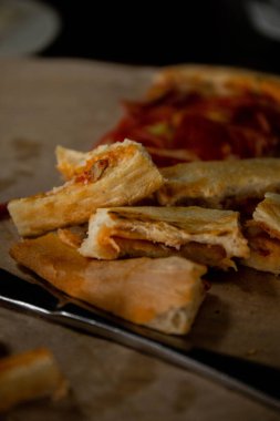 Isırılmış pizza dilimleri bir bıçak ve çatallı pizza kabuğunun yanında bir tepside duruyordu.