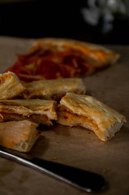 Isırılmış pizza dilimleri bir bıçak ve çatallı pizza kabuğunun yanında bir tepside duruyordu.