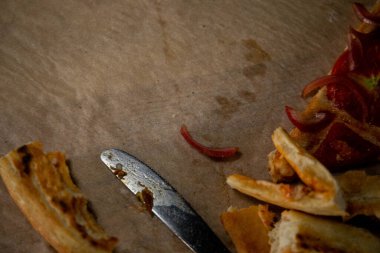 Isırılmış pizza dilimleri bir bıçak ve çatallı pizza kabuğunun yanında bir tepside duruyordu.