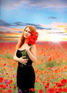 Elinde kırmızı haşhaş buketi tutan siyah elbiseli güzel kızıl saçlı bir kadının çarpıcı portresi. Çiçekler. Yaz. Moda ve güzellik konsepti. 