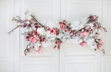 Beyaz bir duvarda suni çiçeklerin çiçek dekoru. Tasarım ve dekorasyon konsepti. Boşluğu kopyala