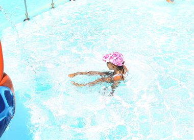 Şapkalı ve mayosu olan küçük bir kız tatilde havuzda oynuyor. Denizde çocukların eğlencesi. Çocuklarla tatile. Yaz 