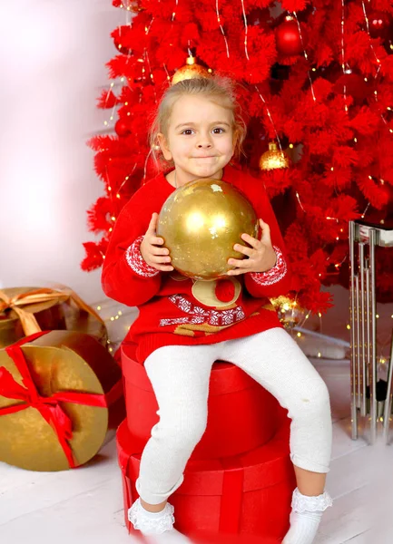 Schattig Blank Meisje Een Rode Kersttrui Spelend Met Een Gouden Stockfoto