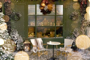 İçinde masalar, karla kaplı Noel ağaçları, ışıklar, tatil dekorları ve içi fırınlanmış mallarla dolu bir vitrin bulunan bir Fransız pastanesinin önünde yeni yıl süslemeleri olan bir afiş. Boşluğu kopyala