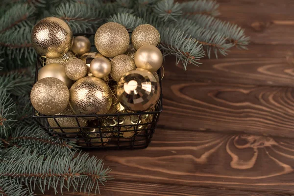 白色木制背景和圣诞树枝条上的精美的圣诞金制玩具桶 — 图库照片