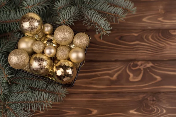 木制背景和圣诞树枝条上的精美的圣诞金制玩具桶 — 图库照片