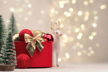 Bokeh 'in arka planında altın bir yay ve geyik olan kırmızı Noel hediyesi kutusu..