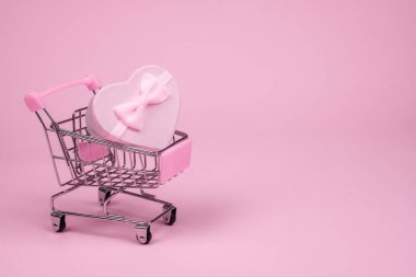 Pembe kalp hediyesi, Sevgililer Günü 'nde pembe arka planda alışveriş scart, hediye teslimatı.