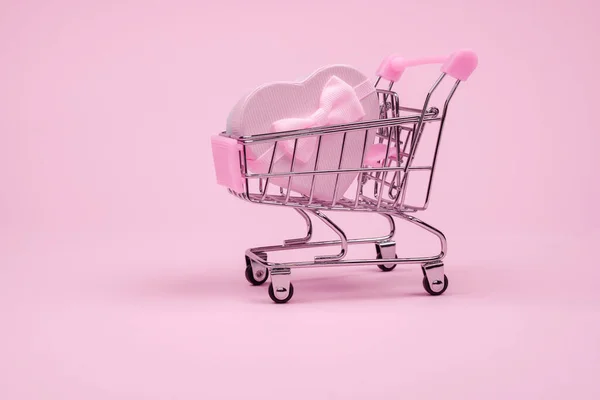 발렌타인 데이에 리본이 달린 핑크 하트 선물이 분홍색 배경의 쇼핑 드레스를 입은 채 배달되고 있습니다. — 스톡 사진
