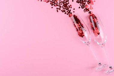 Pembe bir sevgililer gününde, kalp şeklinde pullarla dolu iki kadeh şampanya..