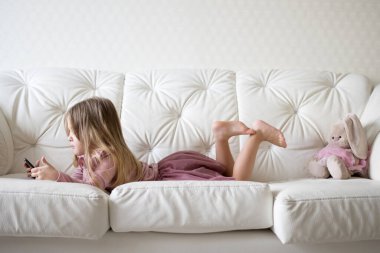 Yatakta sosyal internette tablet oynayan küçük bir kız. Küçük kızın dijital tabletten video izlemesini kapat.