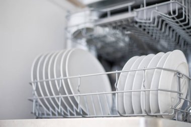 Büyük ve küçük beyaz tabaklar bulaşık makinesine yüklenir.