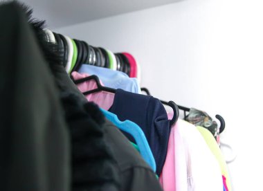 Ev gardırobundaki askılarda asılı renkli kıyafetler. Küçük uzay örgütü.