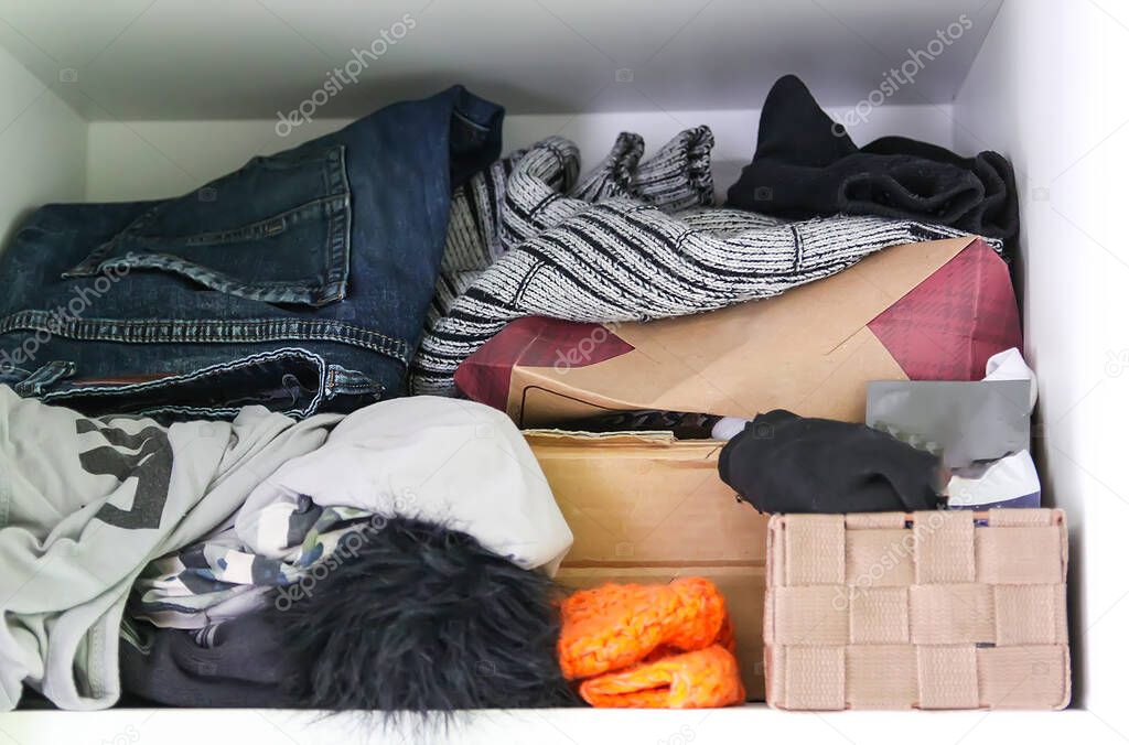 Home wardrobe with different clothes. Small space organization. Disorder. Vertical storage box