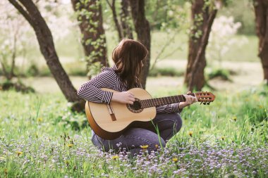 Bahar bahçesinde gitar çalan çekici sarışın genç kız..