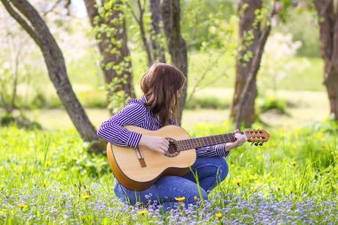 Bahar bahçesinde gitar çalan çekici sarışın genç kız..