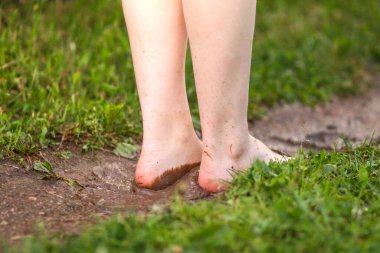 Kırsal kesimdeki yaz yağmurundan sonra çıplak ayaklı kız su birikintilerinde yürüyor..