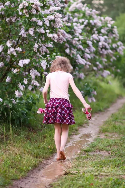 裸足の女の子は田舎の夏の雨の後に水の水たまりを歩く — ストック写真