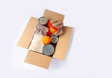 Teneke kutular, taze elma meyveleri, karabuğday ve pirinç paketleri karton bir kutuda. Yemek bağışı, teslimat teması.