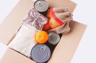 Teneke kutular, taze elma meyveleri, karabuğday ve pirinç paketleri karton bir kutuda. Yemek bağışı, teslimat teması.