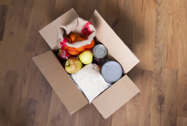 Teneke kutular, taze elma meyveleri, karabuğday ve pirinç paketleri karton bir kutuda. Yemek bağışı, teslimat teması.