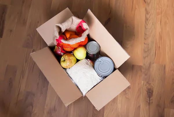 Teneke kutular, taze elma meyveleri, karabuğday ve pirinç paketleri karton bir kutuda. Yemek bağışı, teslimat teması.