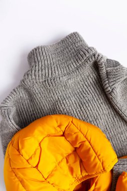 Ilık sarı ceket ve beyaz arka planda yün örgü kazak. Moda kıyafeti. Parlak moda renkler. Ev deposu. Küçük alan düzenleme