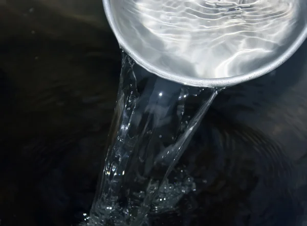 Наливание воды в металлическую чашу — стоковое фото