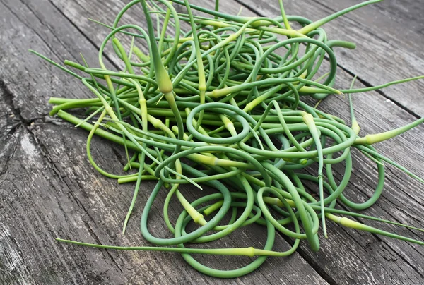 Garlic scapes on old wooden table outdoors — Stock Photo, Image