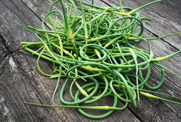 Garlic scapes on old wooden table outdoors — Stock Photo, Image